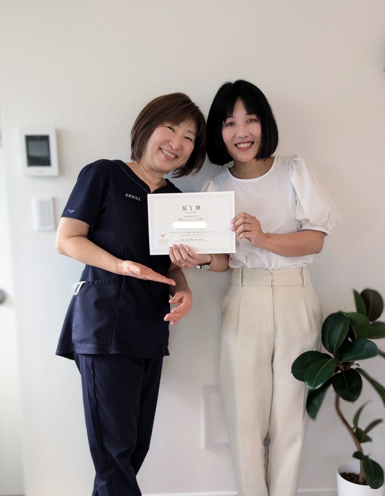 修了証を手に講師と並ぶ受講者